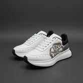 A pair of white Alexander McQueen Sprint Runner sneakers with a silver Seal logo and black heel tab, displayed on top of the official white shoe box.